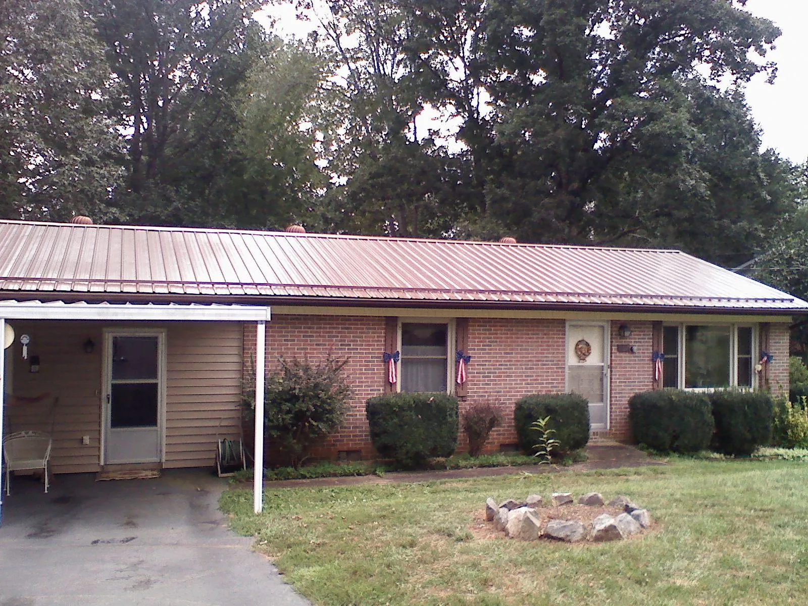 Bronze metal roof and carport on a brick ranch home — Roof Repair work by our crew in Evans